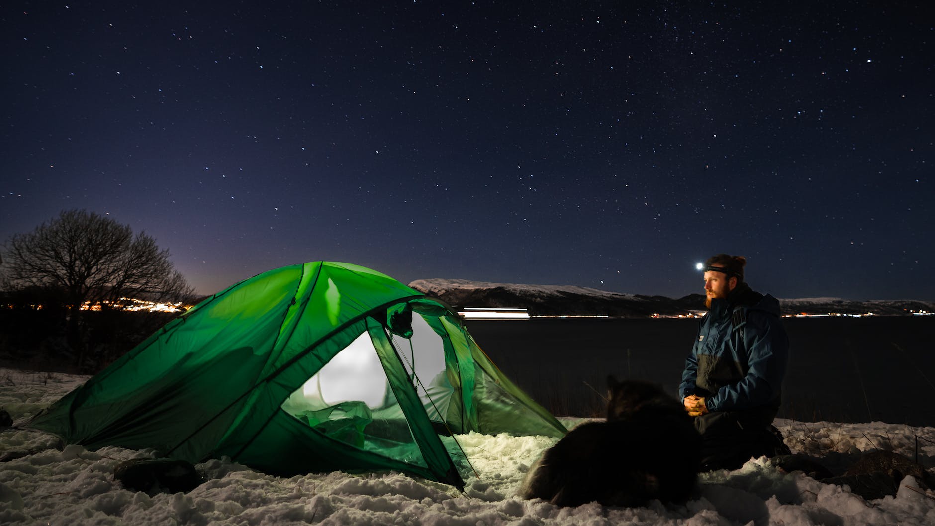 man near tent on winter camping in fjords